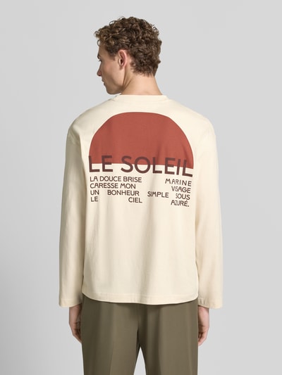 Männermodel trägt Relaxed Fit T-Shirt aus reiner Baumwolle Modell 'AXMAX' von Selected Homme in Creme mit braunem Print, Herren T-Shirt, Ganzkörperansicht Rückansicht.