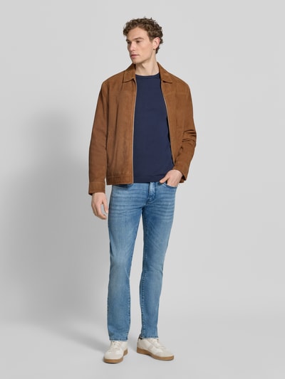 Męski model nosi Tapered Fit Jeans im Used-Look Modell 'Lyon' od Pierre Cardin, dżins bawełniany z domieszką wiskozy, jasnoniebieski, kieszenie ukośne, Szerokość w rozmiarze 32/32: 42 cm, długość nogawki od wewnątrz w rozmiarze 32/32: 79 cm, widok całej sylwetki z przodu.
