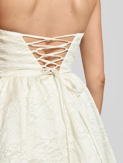 Frauenmodel trägt Minikleid mit floralem Allover-Stitching von Hey Kyla, weiß, florale Struktur, ausgestellte Passform, Detailaufnahme Rücken.