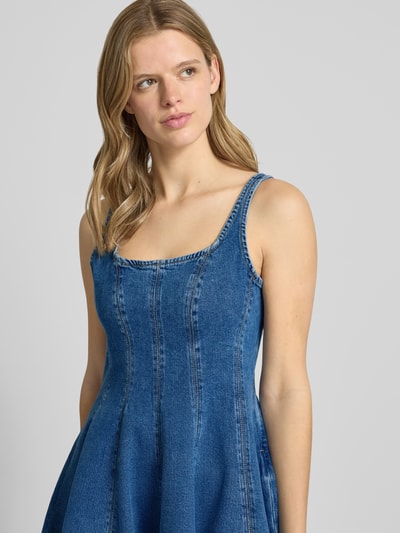 Frauenmodel trägt A-Linie Jeanskleid aus reiner Baumwolle Modell 'GADEME' von Hugo Blue in Denim-Optik mit Karree-Ausschnitt, Nahaufnahme Oberkörper.