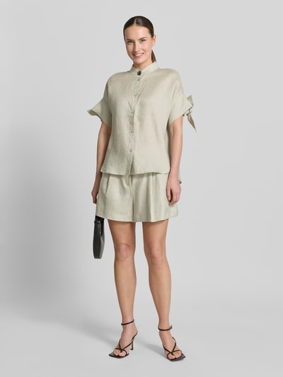 Frauenmodel trägt Regular Fit Bluse mit Stehkragen und Knopfleiste von ARMANI EXCHANGE in hellem Beige mit Knotendetail an den Ärmeln, Rückenlänge 67 cm, Ärmellänge 20 cm, Ganzkörperansicht von vorne.