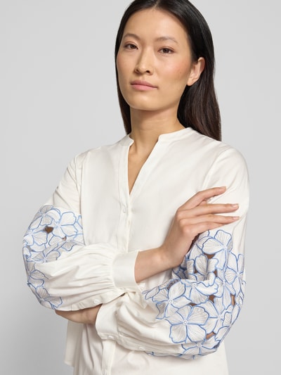 Kobiece modelka nosi Regular Fit Bluse mit Stitchings od HERZENS z mieszanki bawełny i elastanu, hafty, dekolt w serek, listwa guzikowa, długość tyłu w rozmiarze 36: 64 cm, długość rękawów w rozmiarze 36: 61 cm, jasny kolor z niebieskimi haftami na rękawach, zbliżenie na górną część ciała.