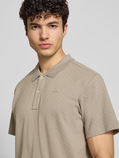 Mężczyznamodel nosi Regular Fit Poloshirt mit Logo von G-Star Raw z czystej bawełny, krój regular fit, z logo i listwą guzikową, beżowy kolor, tekstura gładka, zdjęcie w zbliżeniu na górną część ciała, widok z przodu.