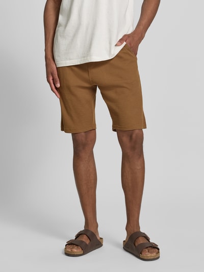 Männermodel trägt Relaxed Fit Sweatshorts aus Baumwoll-Mix von s.Oliver RED LABEL, Optik: Unifarben, Materialverarbeitung: Piqué, Label-Patch, Bundabschluss: Elastisch mit Tunnelzug, seitliche Eingrifftaschen, aufgesetzte Gesäßtasche, Farbe Braun, Textur: Strukturiert, Ganzkörperansicht von vorne.