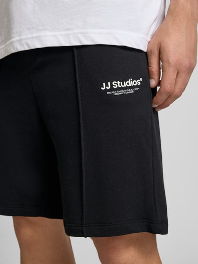Männermodel trägt zwarte Sweatshorts met logo, katoenmix, relaxed fit, elastische tailleband, Sweatshorts met Logo Model 'KANE' van Jack & Jones, detailopname.