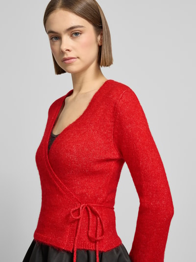 Frauenmodel trägt Cardigan in Wickel-Optik von Gina Tricot in Rot, Material-Mix mit Alpaka-Anteil, Slim Fit, V-Ausschnitt, Nahaufnahme Oberkörper.