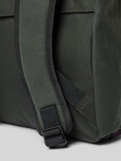 Produktfoto, detailreiche Nahaufnahme grüner Stofftextur mit Gurt aus dem Rucksack mit Label-Patch Modell 'FIELD WAX' von Barbour, Herren Rucksack von Barbour