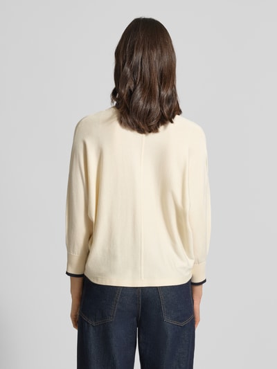 Männermodel trägt Strickpullover aus Viskose-Mix mit V-Ausschnitt von comma, krój regular fit, rękawy z kontrastowymi paskami, długość tyłu 52 cm, długość rękawa 56 cm, kremowy kolor, prosta faktura, Ganzkörperansicht Rückansicht.