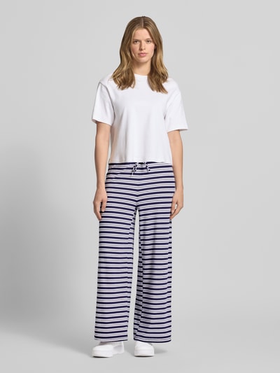 Vrouwenmodel draagt Hose im Allover-Look mit Tunnelzug van Gina Tricot, wit-blauw gestreept, wide leg, elastische tailleband met koord, viscosemix, volledige lichaamsaanzicht van voren.