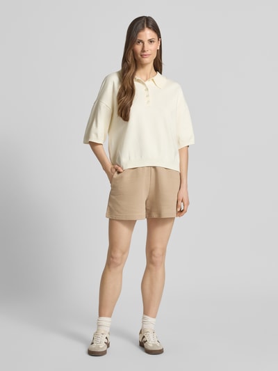 Frauenmodel trägt Relaxed Fit Shorts aus reiner Baumwolle Modell 'NINOSTA-2' von HUGO in Beige, unifarben, Logo-Detail, Ganzkörperansicht von vorne.