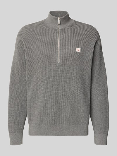 Produktfoto, Loose Fit Troyer mit gerippten Abschlüssen von Calvin Klein Jeans aus grauem Strick, Troyer-Kragen, kurzem Reißverschluss, Label-Detail.