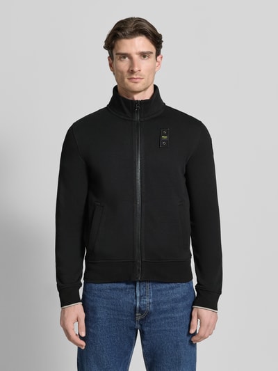 Männermodel trägt Sweatjacke mit Stehkragen Modell 'City New' von Blauer Usa, Schwarz, Baumwoll-Mix, Slim-Fit, Reißverschluss, Label-Detail, Ganzkörperansicht von vorne. Rückenlänge 45 cm, Ärmellänge 84 cm bei Größe M.