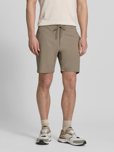Männermodel trägt Straight Fit Shorts mit Eingrifftaschen Modell 'Drift' von SCANDINAVIAN EDITION, beige, elastischer Bund, Ganzkörperansicht von vorne.