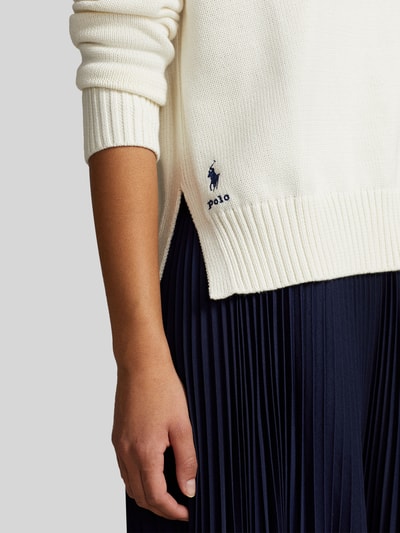 Kobiece modelka nosi Regular Fit Strickpullover aus reiner Baumwolle od Polo Ralph Lauren, kremowy, dzianinowy, z logo, detal boczny, krój regular fit, z długimi rękawami i prążkowanymi ściągaczami, unikalna tekstura, widok zbliżony na górną część ciała.