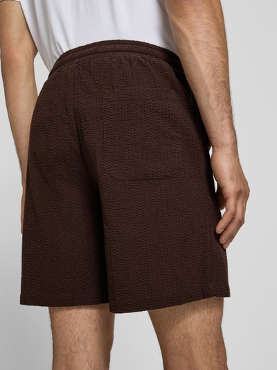 Männermodel trägt Loose Fit Shorts aus reiner Baumwolle Modell 'CRUZ' von Only & Sons in Optik: Unifarben, Materialverarbeitung: Seersucker, Bundabschluss: elastisch, Gesäßtasche sichtbar, Ganzkörperansicht Rückansicht.