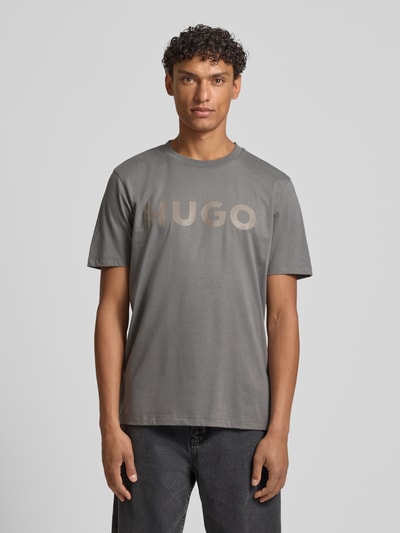 Männermodel trägt Relaxed Fit T-Shirt aus reiner Baumwolle Modell 'DULIVIO' von HUGO in Optik: Unifarben, Label-Schriftzug, Jersey, Ganzkörperansicht von vorne.