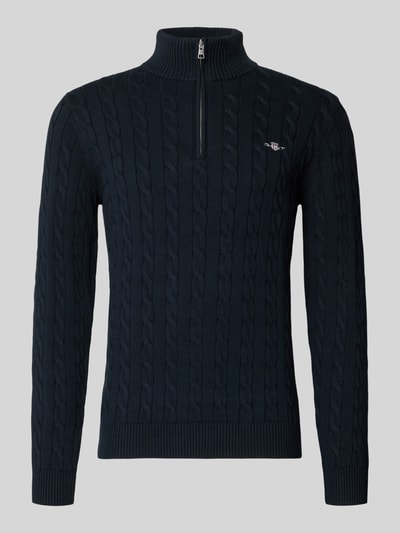 Produktfoto, dunkelblauer Strickpullover mit gerippten Abschlüssen von Gant aus reiner Baumwolle, Slim-Fit, Stehkragen und kurzem Reißverschluss, Logo-Label-Stitching auf der Brust, klassische Struktur mit sichtbarer Zopfstricktextur.