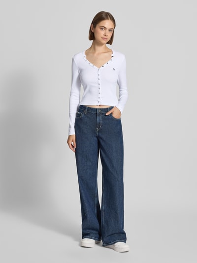 Frauenmodel trägt Slim Fit Longsleeve aus Baumwoll-Mix von GUESS Jeans in Weiß mit durchgehender Knopfleiste und Logo-Stitching, Ganzkörperansicht von vorne