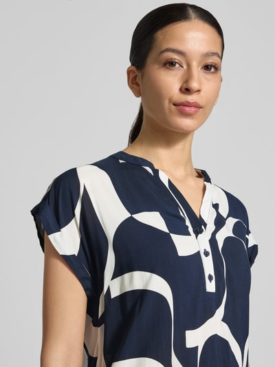 Frauenmodel trägt Regular Fit Bluse aus reiner Viskose Modell 'Miriama' von ZABAIONE in Dunkelblau mit weißem Muster, Tunika-Ausschnitt, kurzärmelig, elastischer Bund, Rückenlänge bei Größe S 62 cm, Nahaufnahme Oberkörper.