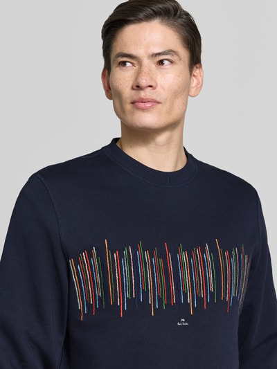 Männermodel trägt Sweatshirt mit Motiv-Stitching von PAUL SMITH aus Reine Baumwolle im Regular-Fit, dunkelblau mit buntem Stitching, Nahaufnahme Oberkörper.