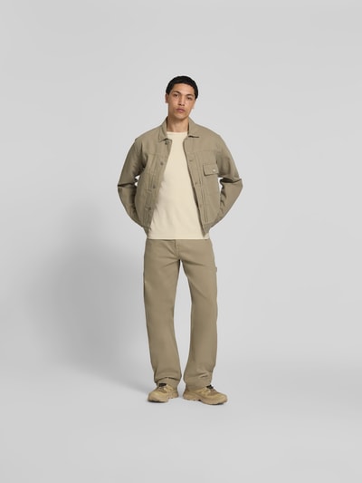Männermodel trägt Relaxed Fit T-Shirt mit Strukturmuster von Forét aus Reine Baumwolle, Rundhalsausschnitt, Logo-Stitching, helles Beige, kombiniert mit passenden Hosen und Jacke, Rückenlänge bei Größe M 69 cm, Ganzkörperansicht von vorne.