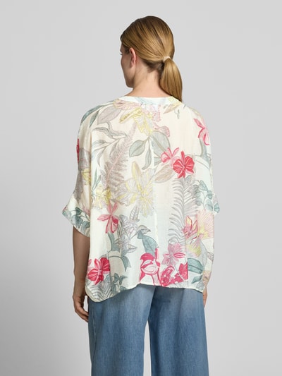 Frauenmodel trägt Relaxed Fit Bluse aus Viskose-Mix im Allover-Look von Comma mit V-Ausschnitt, 3/4-Arm, verlängerter Rückseite, zarten Blumenfarben, samtiger Textur, Ganzkörperansicht Rückansicht.