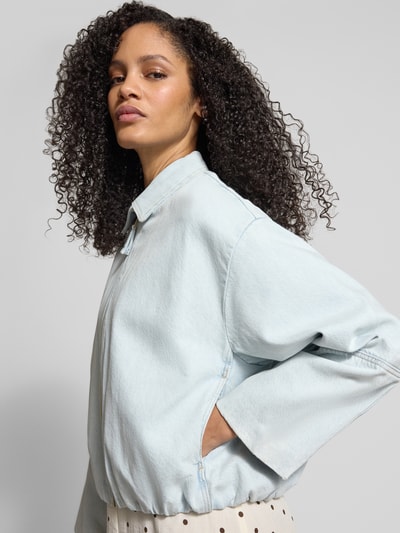 Vrouwenmodel draagt Jeansjacke met Reißverschluss van Jake*s Casual in lichtblauw, relaxed fit, zuiver katoen, detailopname bovenlichaam.