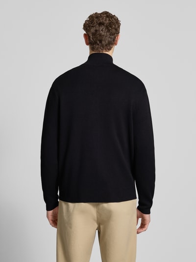 Männermodel trägt schwarze Relaxed Fit Strickjacke aus Viskose-Mix Modell 'TELLER' von SELECTED HOMME, Ganzkörperansicht Rückansicht.