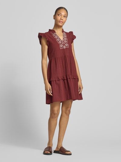 Frauenmodel trägt figurumspielendes Freizeitkleid aus reiner Baumwolle Modell 'Dichte' von Vero Moda, bordeaux, kurzarm, Mini-Länge, tiefer V-Ausschnitt, Struktur durch Flammgarn, unifarben, Ganzkörperansicht von vorne.
