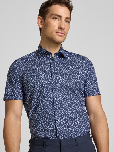 Männermodel trägt OLYMP Level Five Slim Fit Freizeithemd mit floralem Allover-Print, Baumwoll-Mix, Kentkragen, Nahaufnahme Oberkörper.