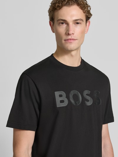 Męski model nosi czarny t-shirt z gładkiej bawełny, z matowym logo BOSS na piersi, Regular Fit T-Shirt aus reiner Baumwolle Modell 'TS_STRUCTURE LOGO 1027473' von BOSS Green, Nahaufnahme górnej części ciała.