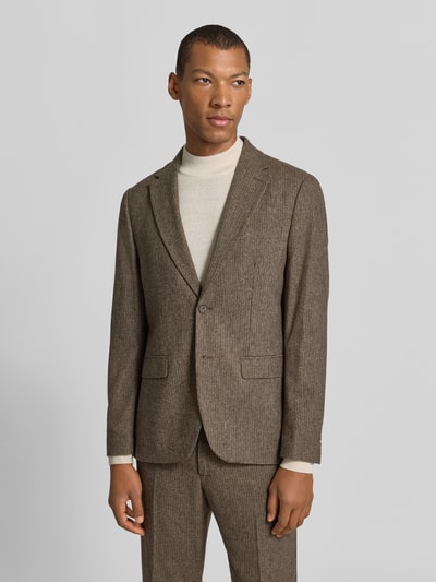Männermodel trägt Slim Fit Sakko mit Pattentaschen aus Wolle von Selected, braune Webware mit Reverskragen, Ganzkörperansicht von vorne.