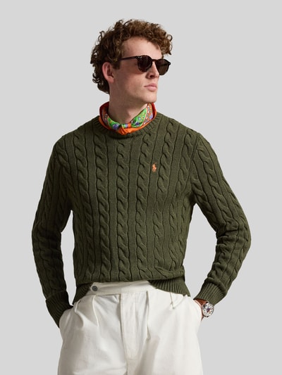 Męski model nosi Regular Fit Strickpullover aus reiner Baumwolle od Polo Ralph Lauren, zielony, wzór warkoczowy, dzianina, długi rękaw, logo, krój regular fit, widok na całą sylwetkę z przodu.