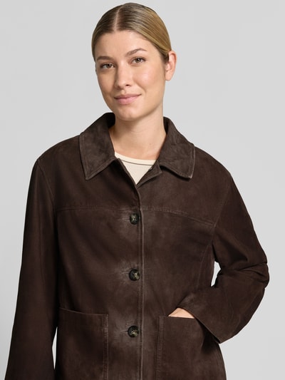 Frauenmodel trägt Lederjacke mit aufgesetzten Taschen von COMMA, braunes Echtleder, Umlegekragen, Knopfleiste, Regular Fit, Nahaufnahme Oberkörper.