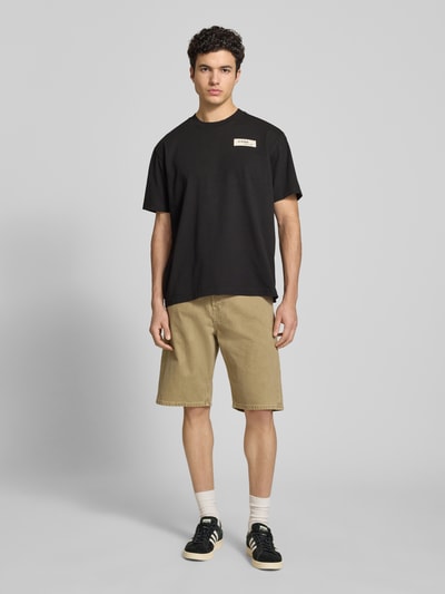 Männermodel trägt Relaxed Fit T-Shirt mit Label-Badge von G-Star Raw in Schwarz aus Reine Baumwolle, Herren T-Shirt, Ganzkörperansicht von vorne. Rückenlänge bei Größe M: 70 cm, Rundhalsausschnitt.