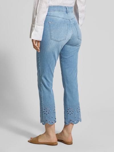 Kobiece modelka nosi spodnie z haftem angielskim model 'KICK' od MAC, wpuszczane kieszenie, skrócony krój, jasnoniebieski denim, szerokość w rozmiarze 36: 41 cm, długość wewnętrzna nogawki w rozmiarze 36: 68 cm, model z tyłu w pełnej długości.