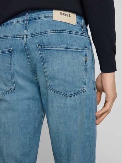 Männermodel trägt Straight Fit Jeans aus Baumwoll-Mix Modell 'MAINE' von BOSS in Denim-Optik mit Nieten, 5-Pocket-Design, Ganzkörperansicht Rückansicht.