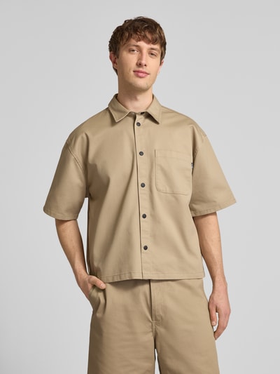 Männermodel trägt Relaxed Fit Freizeithemd mit Brusttasche von REVIEW in Beige, Material-Mix mit Baumwoll-Anteil, Knopfleiste, 1/2-Arm, Kentkragen, Ganzkörperansicht von vorne