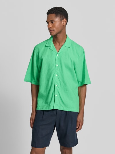 Männermodel trägt Cropped Freizeithemd aus Leinen-Baumwoll-Mix von Lindbergh in Grün mit Reverskragen, Knopfleiste, Ganzkörperansicht von vorne. Rückenlänge bei Größe M: 70 cm, Schulterbreite 49 cm, Ärmellänge 32 cm.