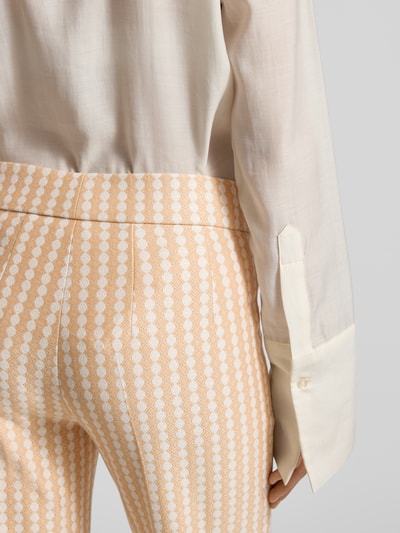 Frauenmodel trägt Stoffhose in verkürzter Passform Modell 'NANETTE' von SEDUCTIVE in Creme und Apricot mit Muster, Nahaufnahme Hüfte, Viskose-Mix mit Stretch-Anteil, lockerer Schnitt, elastischer Bund, Bundfalten