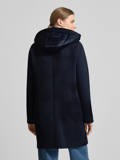 Modelka nosi Płaszcz mit Kapuze und Pattentaschen von Christian Berg Woman Selection, mieszanka materiałów z dodatkiem wiskozy, krój regular fit, kaptur z tunelem, listwa guzikowa, kieszenie z patką, długość tyłu w rozmiarze 36: 88 cm, szerokość ramion: 45 cm, szerokość w rozmiarze 36: 50 cm, długość rękawów: 57 cm, kolor ciemnogranatowy, gładka tekstura, pełny widok z tyłu.