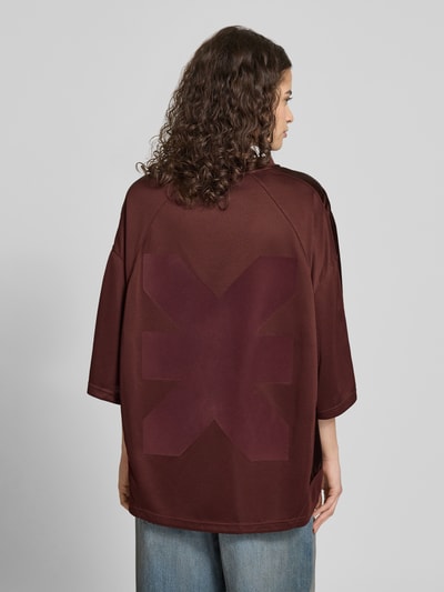 Kobiece model prezentuje Oversized T-Shirt mit Label-Print od Karo Kauer, damski t-shirt, krój oversized, nadruk z logo, dekolt w serek, obniżone ramiona, długość tyłu w rozmiarze S: 71 cm, widok całej sylwetki od tyłu.