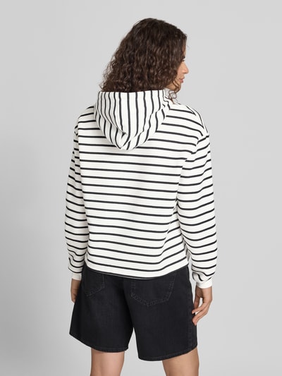 Frauenmodel trägt Regular Fit Hoodie aus Baumwoll-Mix Modell 'CHILLI' von PIECES, weiß mit schwarzen Streifen, lockere Struktur, Ganzkörperansicht Rückansicht.