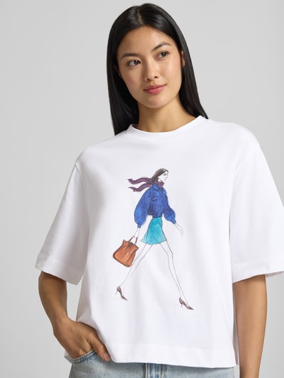 Vrouwenmodel draagt Relaxed Fit T-shirt uit puur katoen met motiefprint, ronde hals, ruglengte maat S: 50 cm van Rich & Royal. Nahaufnahme Oberkörper.