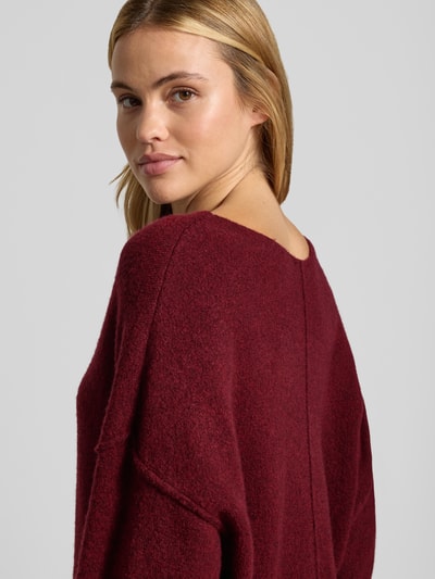 Frauenmodel trägt Relaxed Fit Strickpullover aus Material-Mix mit Leinen-Anteil von American Vintage in Dunkelrot, texturierte Oberfläche, überschnittene Schultern, Nahaufnahme Oberkörper, Rückenansicht. Damen Strickpullover, gerippte Abschlüsse, Rundhalsausschnitt, Rückenlänge 50 cm, Ärmellänge 60 cm.
