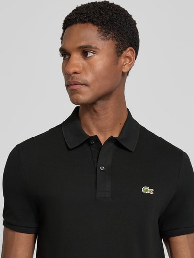 Männermodel trägt Slim Fit Poloshirt aus reiner Baumwolle von Lacoste, Herren Poloshirt, czarny kolor, struktura gładka, Nahaufnahme Oberkörper