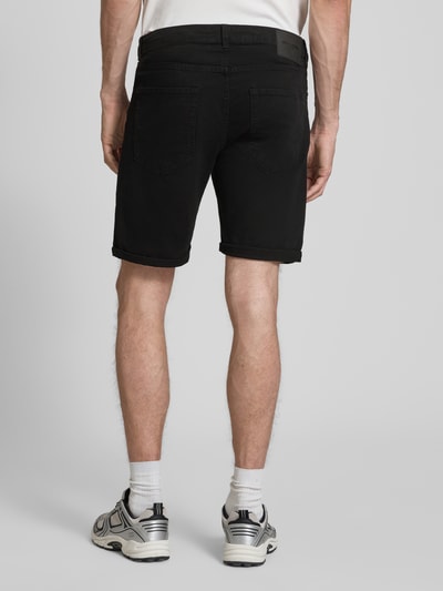 Männermodel trägt schwarze Jeansshorts mit Umschlag und Eingrifftaschen, Modell 'RICK ALLEN' von Jack & Jones, Rückansicht Ganzkörperansicht. Regular Fit, Baumwoll-Elasthan-Mix, Kontext: Bundweite M 43 cm, Innenbeinlänge M 20 cm.