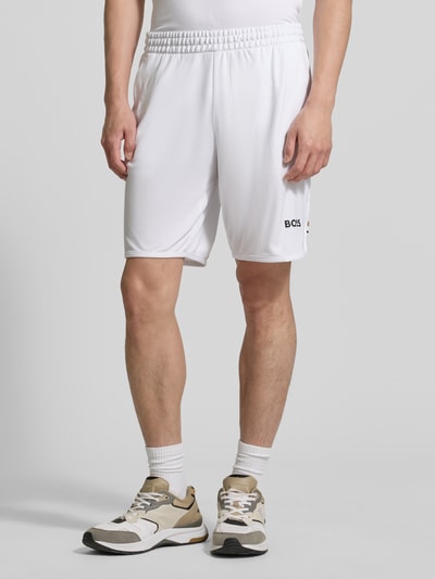 Männermodel trägt Relaxed Fit Sport-Shorts mit Logo-Print Modell 'SH_TOC SPIN 9 INCH' von BOSS Green, Optik: Unifarben, Kontraststreifen, Tunnelzug, Beinabschluss: elastisch, seitliche Eingrifftaschen, Ganzkörperansicht von vorne.