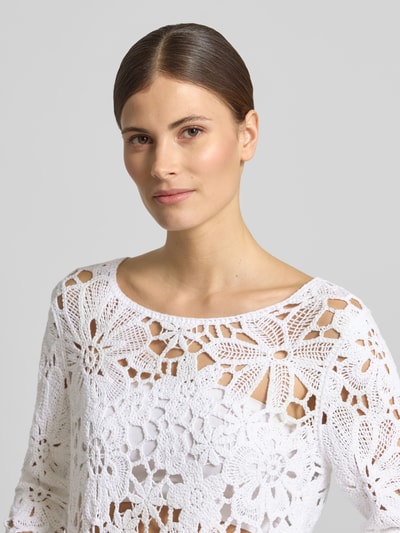 Frauenmodel trägt Strickshirt mit Häkelspitze Modell 'Cornelly' von monari, weißer Baumwoll-Mix, Rundhalsausschnitt, Nahaufnahme Oberkörper.
