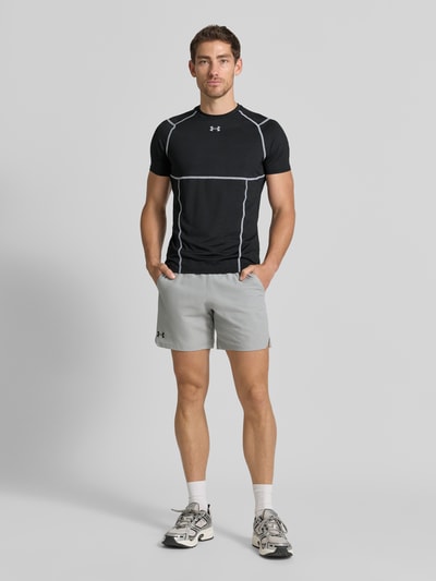 Mannenmodel draagt t-shirt met logoprint en raglanmouwen van Under Armour, zwart met witte naden, materiaalmix met stretch, elite fit, ronde hals, ruglengte maat M 69 cm, geheellichaamsaanzicht van voren.